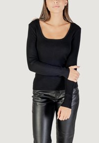 Maglione lungo a maniche lunghe nero a coste con scollo quadrato, design aderente e tessuto testurizzato, abbinato a pantaloni in pelle nera lucida.