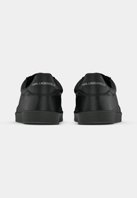 Μαύρα δερμάτινα αθλητικά παπούτσια με λεία υφή, στρογγυλή μύτη και επίπεδη λαστιχένια σόλα. Φέρουν το λογότυπο "KARL LAGERFELD" στη φτέρνα.