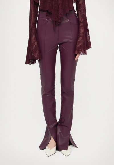 Pantalon en simili cuir bordeaux à la coupe ajustée, avec des fentes latérales à l'ourlet et une texture lisse et brillante.