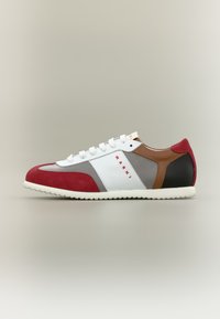 Baskets en daim et cuir rouge avec un design blanc et gris, des accents contrastés marron et noir, et une semelle texturée. Marque visible sur le côté.