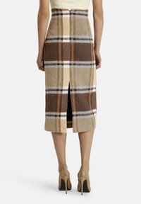 Ceļa garuma vilnas svārki ar brūnu un bēšu rakstu, ar aizmugurējo izgriezumu un pieguļošu siluetu.