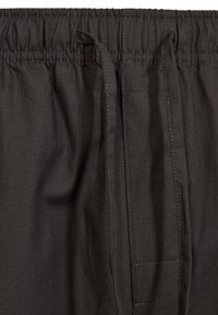 Black fabric with a textured weave, featuring an elastic waistband and drawstring, with visible stitching and a side pocket detail.