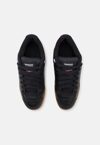 Chaussures de sport noires avec tige en textile et cuir, semelle en caoutchouc, lacets plats, col rembourré et logo Reebok Classic sur la languette.