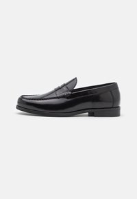 Černé kožené pánské penny loafer boty s nízkým podpatkem, se švy na špičce a hladkým lesklým povrchem, zobrazené v profilu na bílém pozadí.