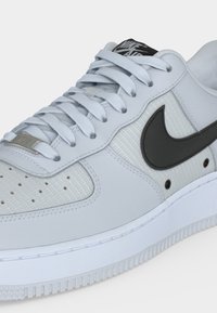 Ανοιχτό γκρι sneaker Nike Air με λευκή σόλα, μαύρο λογότυπο Swoosh και ταιριαστά ανοιχτό γκρι κορδόνια σε υφασμένα επάνω πάνελ.