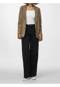 Blazer s leopardím potiskem a ohrnutými rukávy, doplněný o černé široké džínové kalhoty s vysokým pasem. Bílé tričko a černé sneakers dotvářejí outfit.