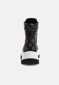 Zapatilla de deporte negra y marrón con diseño de caña alta, material texturizado y suela blanca. Presenta un logo en la parte trasera y una lengüeta.