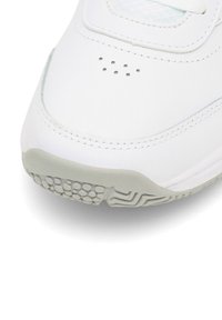 Detailný záber bielej tenisky s perforovanými ventilačnými otvormi a svetlošedou štruktúrovanou gumovou podrážkou.