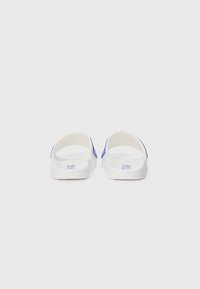 White slide sandals with a textured sole and blue accents. Open back design, minimalistic style, featuring brand text on the footbed.