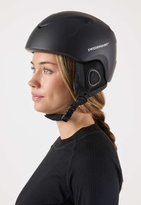 Schwarzer Skihelm mit verstellbarem Riemen, Netzbelüftung und seitlicher Polsterung. Verfügt über eine matte Oberfläche und ein Markenlogo an der Seite.