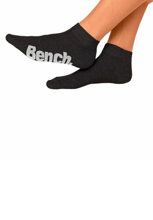 Schwarze Knöchelsocken aus einem strukturierten Stoff mit dem Wort "Bench" in weißer Schrift an der äußeren Seite.