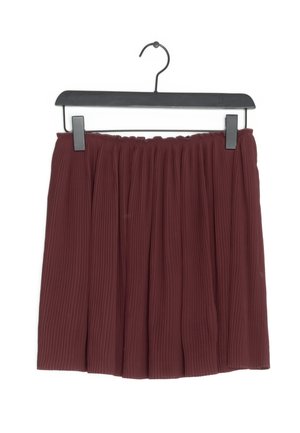 Jupe plissée bordeaux suspendue sur un cintre en plastique noir avec des pinces sur fond blanc.