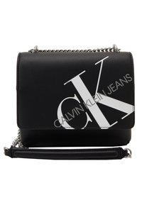 Černá crossbody taška Calvin Klein Jeans se stříbrným řetízkovým popruhem a velkým bílým logem "CK" na přední klopě.