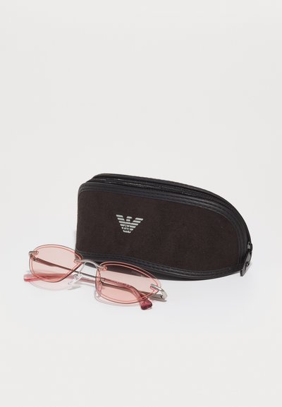 Pink-tinted rectangular sunglasses with silver metal accents, next to a black suede zippered case featuring a silver logo.