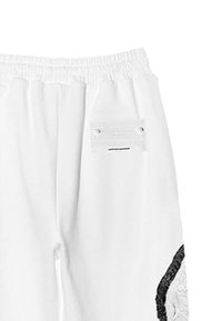 Pantalones de chándal blancos con cintura elástica, que cuentan con un parche texturizado negro en el lado izquierdo y un detalle de bolsillo transparente en la parte posterior.
