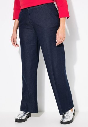 Mørkeblå denimbukser med lige ben-design, der har en medium høj talje og klassiske lommer. Kombineret med blændende sølvfarvede sko.