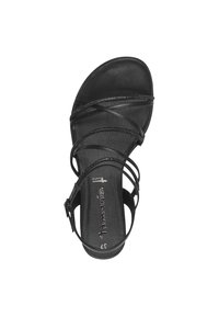 Svart sandal med flera tunna remmar, platt sula och spänne. Innersulan har en texturerad yta och en märkesetikett.