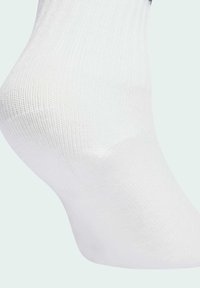 Biele bavlnené ponožky s rebrovanou textúrou, zakriveným tvarom a bezšvovým prstom. Mäkko tkanina, vhodná na neformálne nosenie.