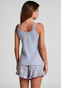 Lichtblauw geript tanktop met geschulpte kanten schouderbandjes, gecombineerd met bloempatronen shorts met ruches aan de zomen in zachte pasteltinten.