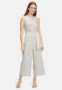 Jumpsuit senza maniche di un grigio chiaro, con un design a gamba larga e una cintura annodata in vita. Realizzato in tessuto liscio, presenta una silhouette semplice e pulita.