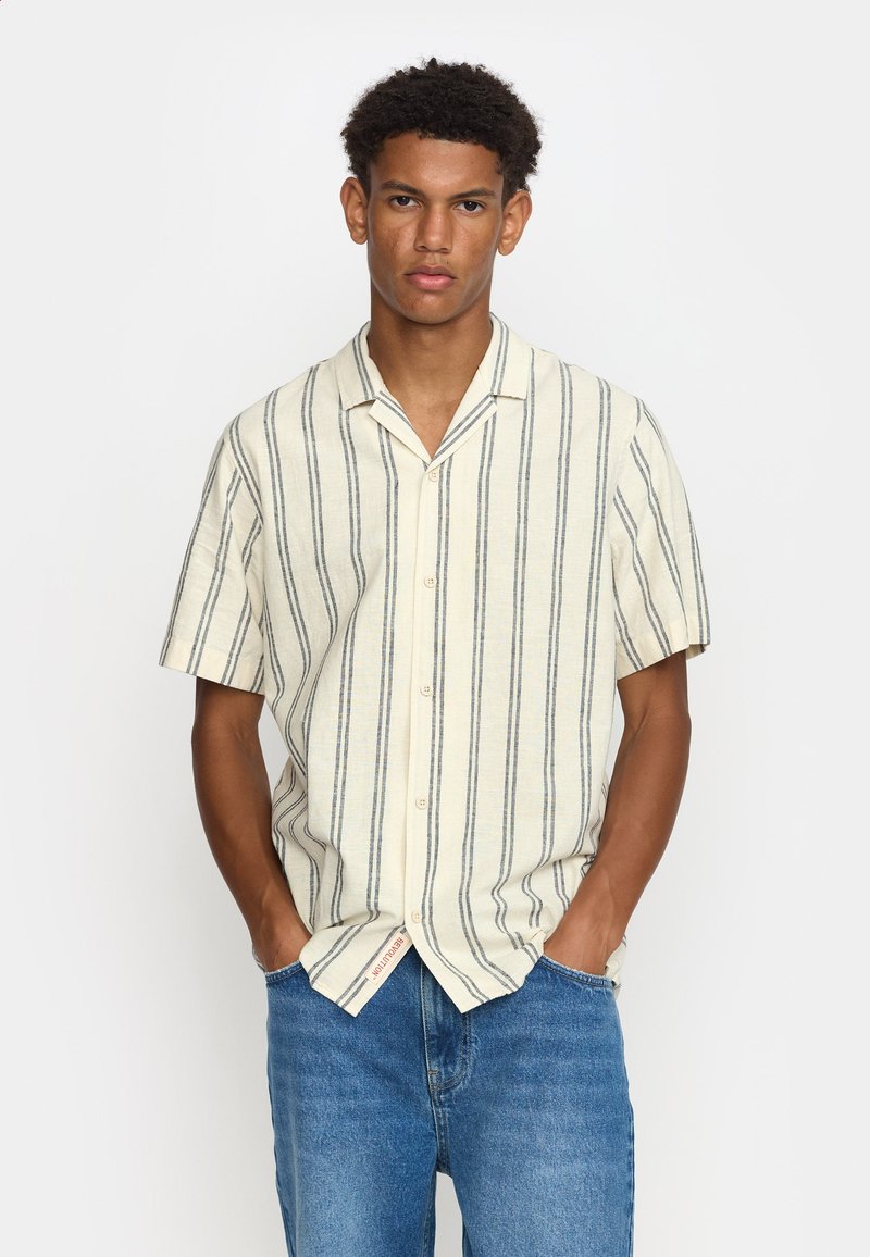 Korte mouwen overhemd in lichtcrème met marineblauwe verticale strepen, met knoopsluiting, relaxte pasvorm en zachte textuur, gecombineerd met blauwe denim jeans.