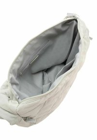 Sac matelassé gris clair avec une fermeture éclair, doté d'un intérieur doublé et d'une petite poche zippée. Texture douce et forme arrondie.