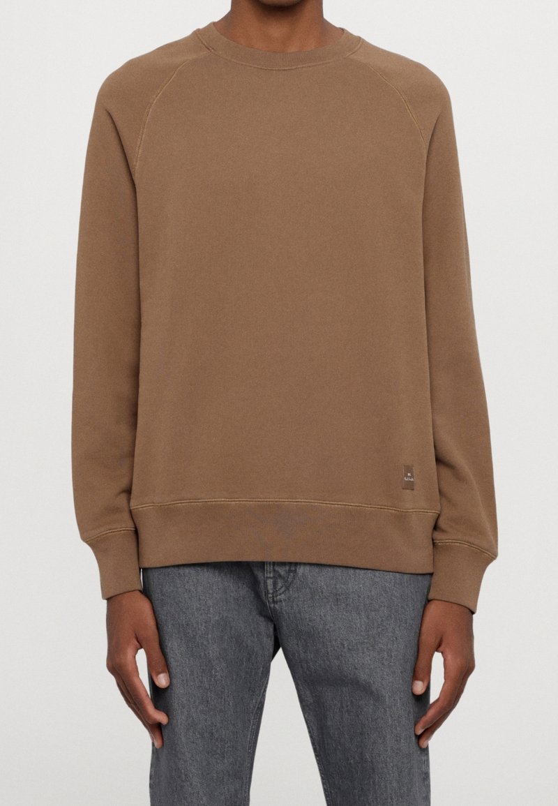 Bruine sweatshirt met geribde ronde hals en manchetten. Heeft raglanmouwen en een klein logo-label aan de onderlinkerkant. Zachte stofstructuur.