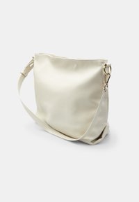 Hvid læder skuldertaske med en struktureret overflade, justerbar rem og hardware i guld tone. Har et enkelt, uprydet design.