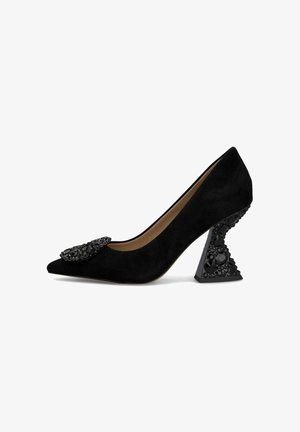 Décolleté in suede nera con tacco alto, punta affilata e dettagli in cristallo nera sul superiore, con un tacco a blocco testurizzato e dal design unico.