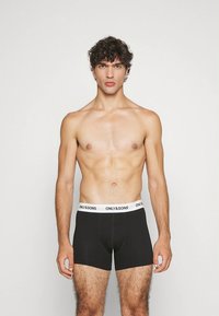 Zwarte boxershorts met een witte tailleband waarop "ONLY & SONS" staat. Het materiaal lijkt zacht en rekbaar.