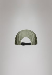 Boné verde-oliva em material de nylon, com aba curvada e strap ajustável na parte de trás. Apresenta detalhes de costura e um orifício de ventilação.