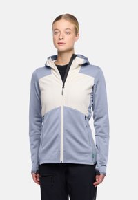 Lichtgewicht, two-tone softshell jack in lichtblauw en crème, met een ritsenkraag, capuchon en textiel met zijzakken.
