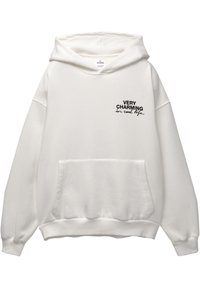 Hoodie blanc en tissu doux, avec une poche avant, de coupe oversized, et texte imprimé en noir : "TRÈS CHARME EN VRAI".