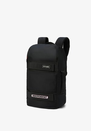 Mochila negra hecha de material duradero con correas de hombro acolchadas, presenta un bolsillo frontal con el texto "INDEPENDENT" y un cierre de cremallera.