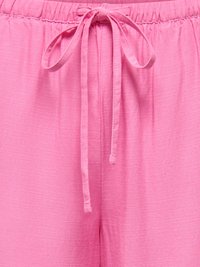 Pantaloni in tessuto rosa tenue con vita elastica e coulisse annodata al centro davanti.