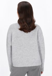 Grauer gestrickter Pullover mit strukturiertem Muster, überschnittenen Schultern und geripptem Saum. Der Stoff wirkt weich und gemütlich, ideal für legere Kleidung.