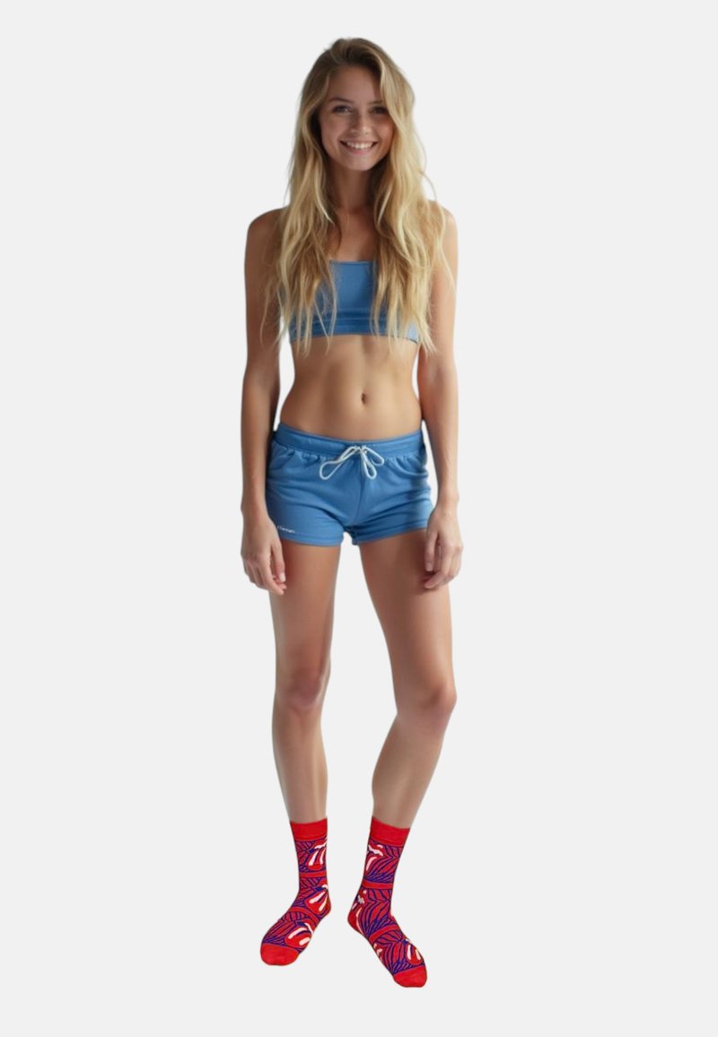 Blå crop top og matchende shorts med snor. Røde sokker med et farverigt bladmønster. Model står på en neutral baggrund.