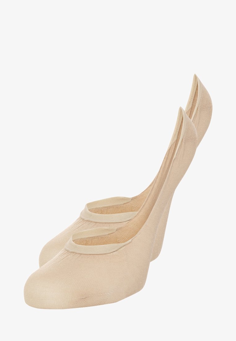 Beige ballet flats with a smooth texture, rounded toes, and pronounced back support. Features a decorative elastic band across the foot.