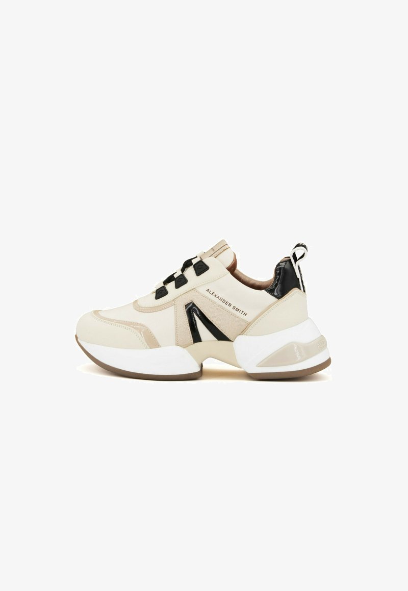 Sneaker beige con accenti neri, caratterizzati da una suola bianca spessa, design geometrico ed elementi decorativi in metallo sulla parte superiore.
