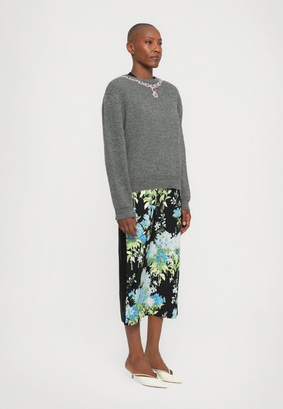 Grau gerippter Pullover, florale Midiröcke mit blauen und grünen Mustern auf schwarzem Hintergrund und cremefarbene, flachabsätzige Mules.
