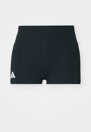 Svart trening shorts laget av elastisk stoff, med høy midje, tettsittende fasong, og hvit Adidas-logo på venstre side.