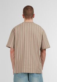 Short-sleeve, beige shirt with vertical white stripes, made of soft cotton, featuring a relaxed fit and a round neckline.