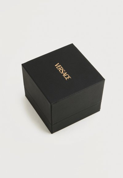 Boîte carrée noire avec le logo doré "Versace" sur le couvercle, présentée fermée sur un fond blanc uni.