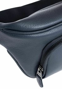 Ciemnoniebieska skórzana torba o gładkiej fakturze, zaokrąglonym kształcie i widocznym zamku błyskawicznym z boku, z metalowym uchwytem.