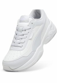 Baskets blanches Puma avec design à lacets, bout perforé, semelle rembourrée et logo Puma sur la languette et le panneau latéral.