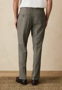Grey structured trousers with a textured finish, featuring two back pockets, a straight leg design, and worn with black shoes.