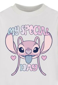 Hvid kortærmet t-shirt med en tegneseriefigur med store ører, tunge ude, og tekst der siger "MIN SPECIELLE DAG" i farverige skrifttyper.