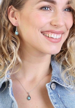 Zilveren juwelenset met druppelvormige turquoise stenen. Oorbellen met haakontwerp, hanger aan een fijne ketting, gestructureerde metalen accenten.