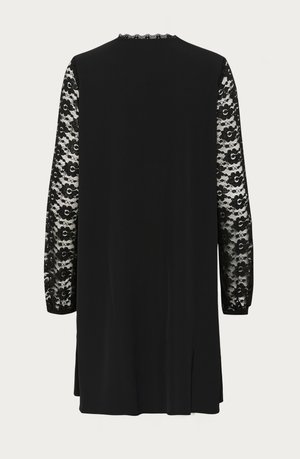 Abito nero con maniche lunghe in pizzo floreale, scollatura tonda con bordatura ondulata e spacco sul retro per facilitare i movimenti.