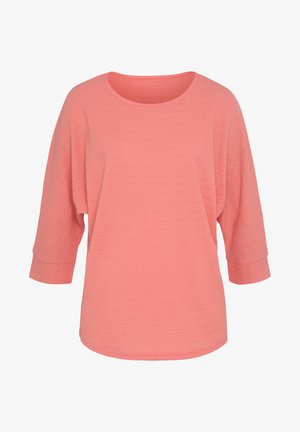 Koralli roosa pullover, millel on tekstureeritud viimistlus, ümmargune kaelus ja kolmeveerandi varrukad. Laisk lõikega ja peente õmblusdetailidega.